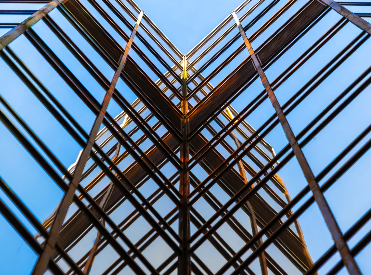Glass and steel building facade viewed from below against a blue sky