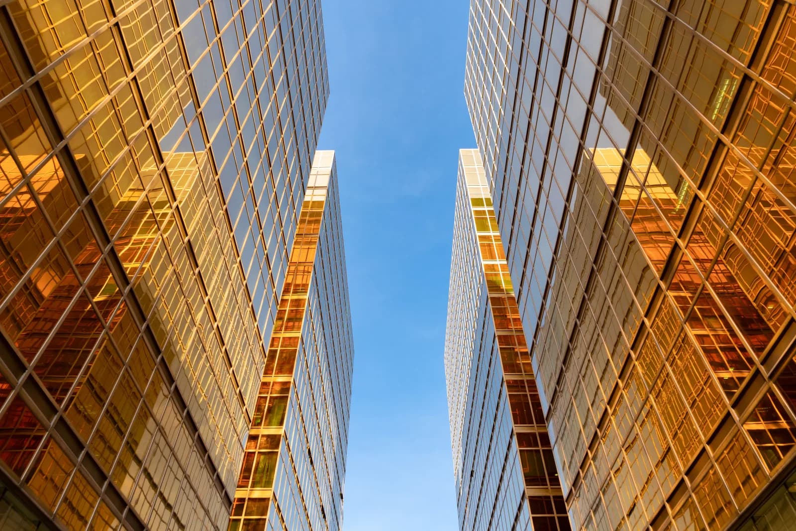 Twin glass office towers viewed from below against a blue sky